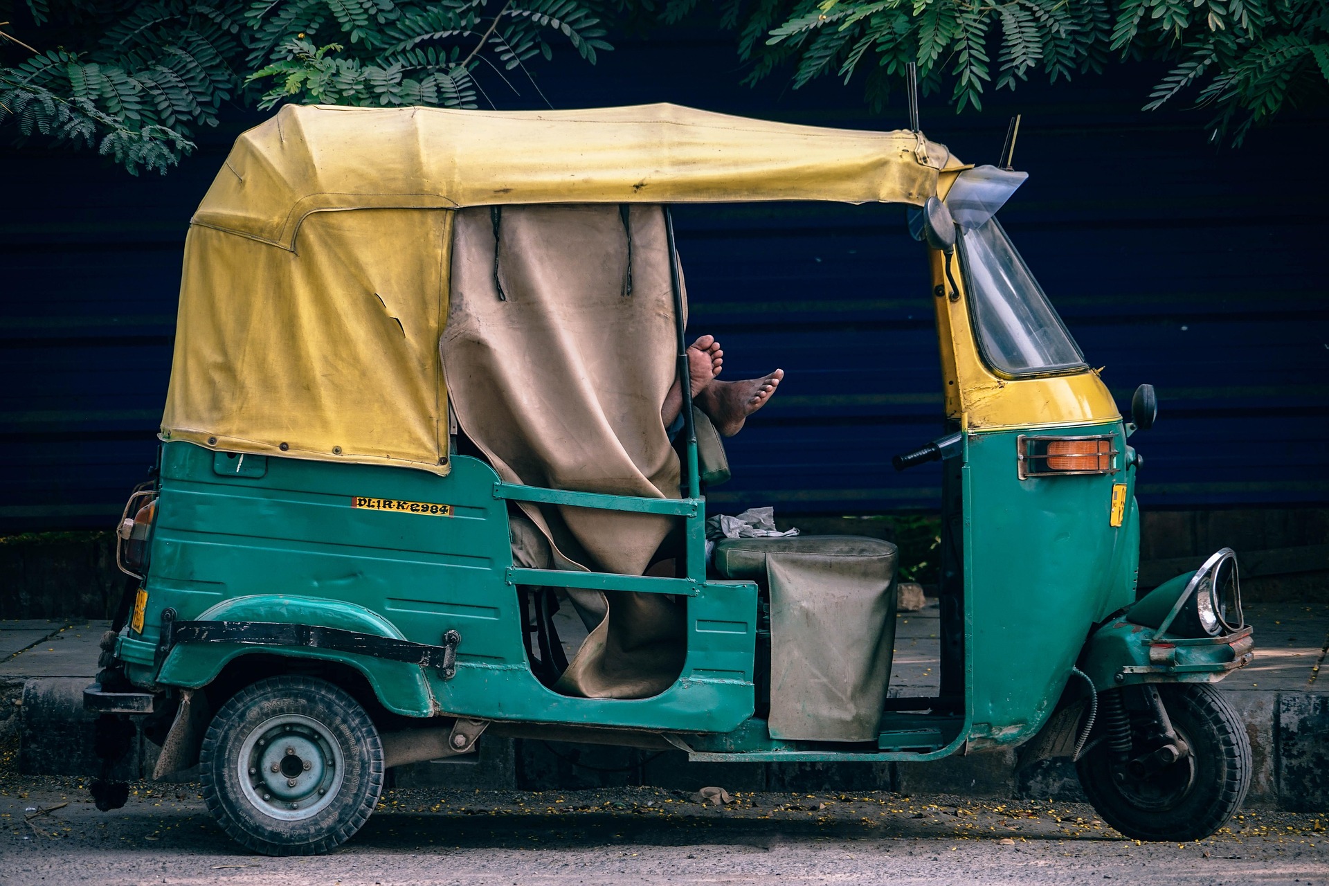 A green and yellow auto-rickshaw parked on a street