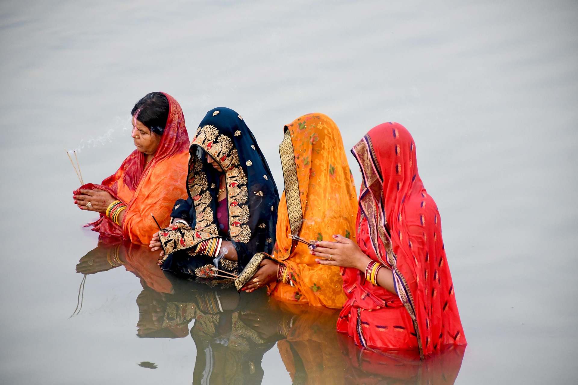 Women in colourful sarees standing in a river during the Chhath Puja festival
