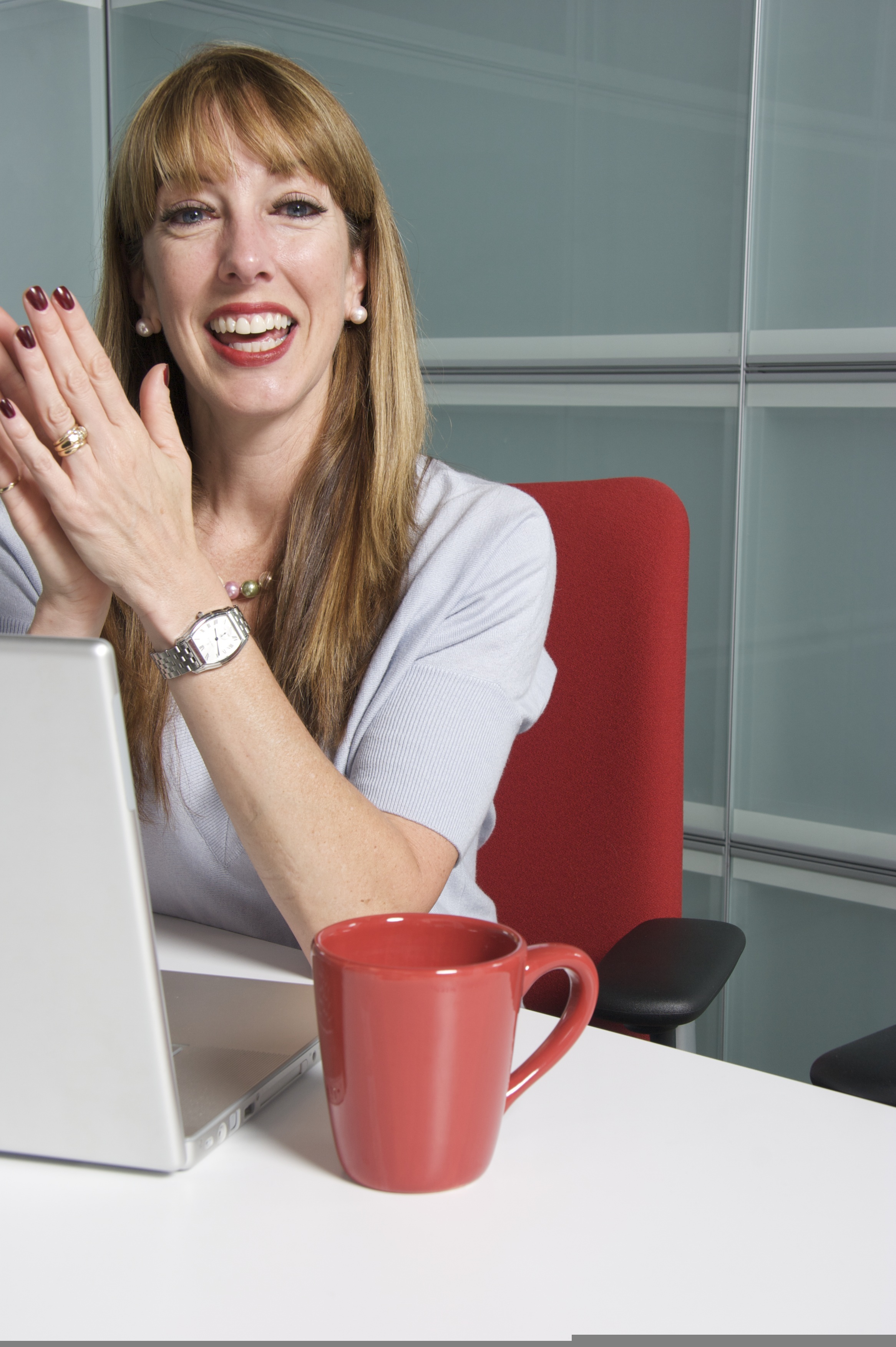 A person laughing, delighted, working at a laptop