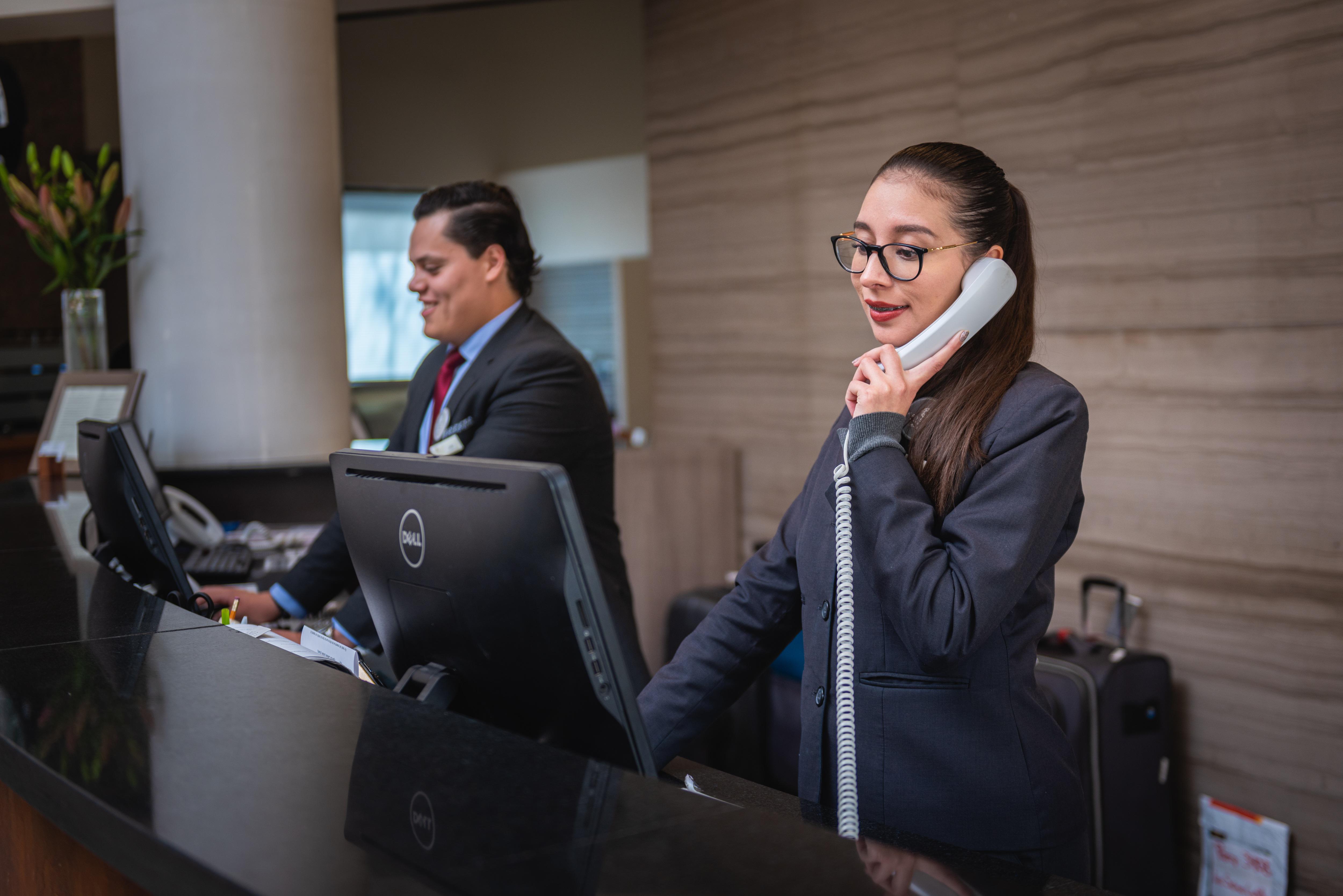 Hotel receptionist answering the phone at the front desk