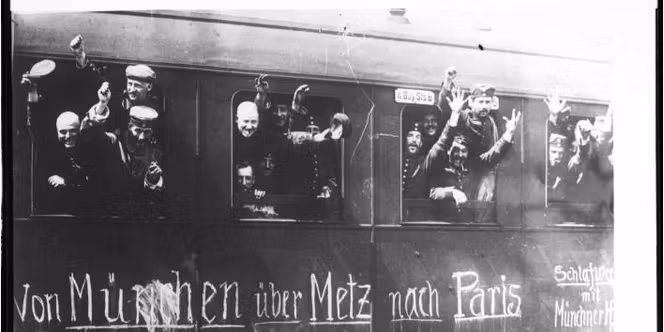 Historisches Foto: Deutsche Reservisten winken jubelnd aus einem Eisenbahnwaggon, auf den mit Kreide 'Von München über Metz nach Paris' geschrieben wurde