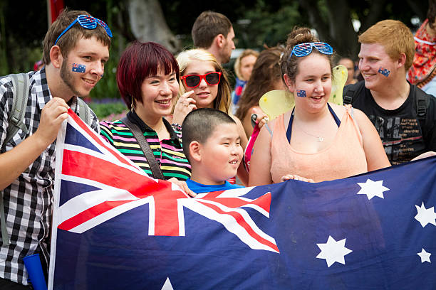 A diverse group of young people celebrating together in Sydney, holding an Australian flag