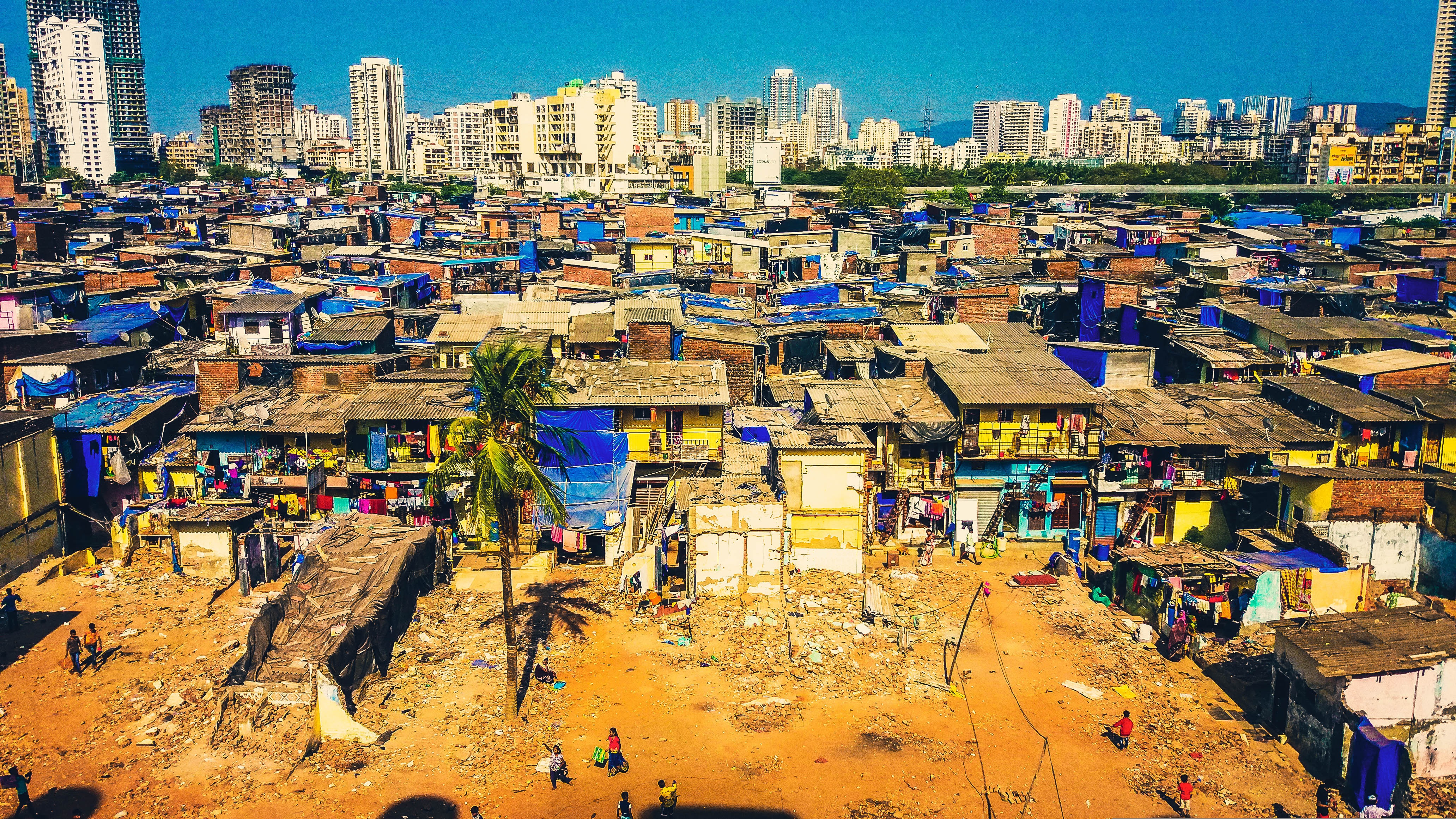 An informal settlement in Mumbai in the foreground, with high-rise apartment towers in the background