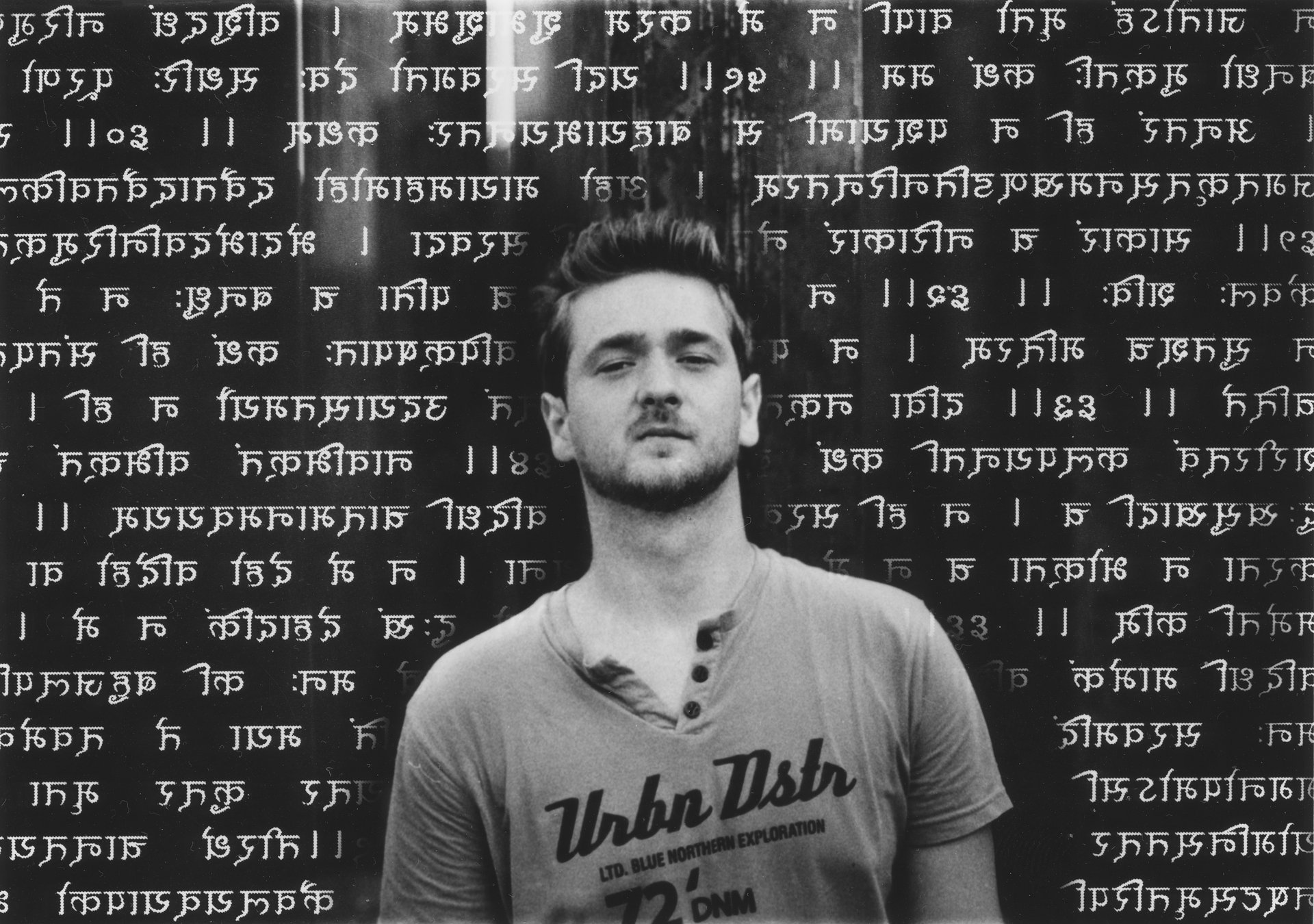 A young person in streetwear, portrayed against a backdrop of ancient Sanskrit script
